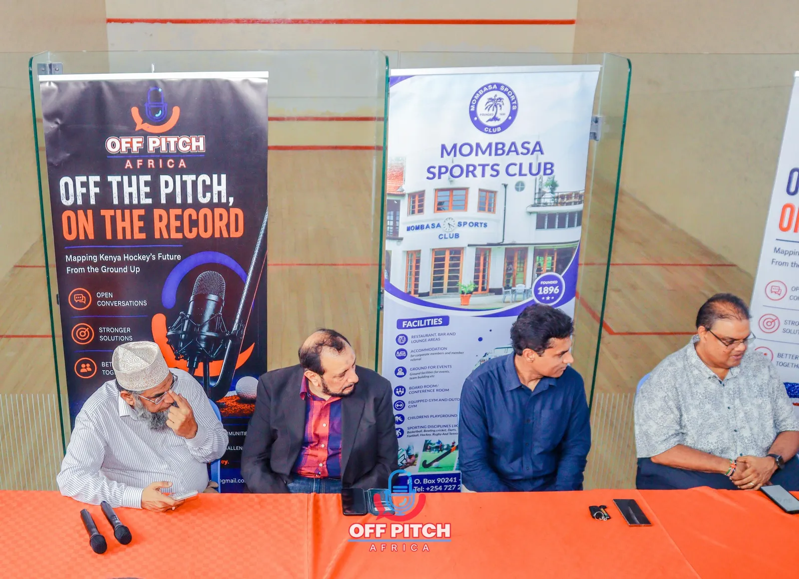 Panelists seated at the table in front of the event banners